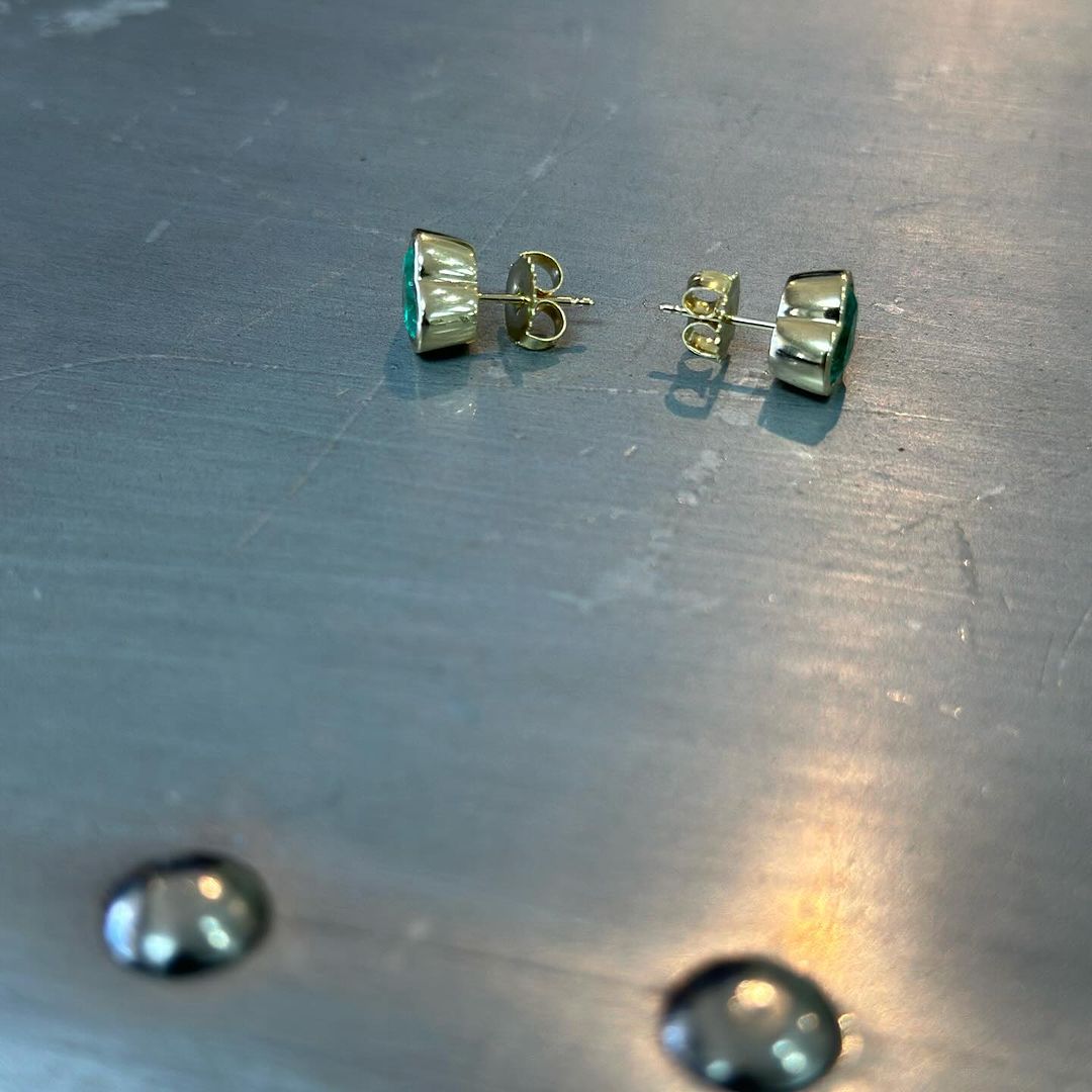 2.84tcw pair of Muzo emerald studs from side view.