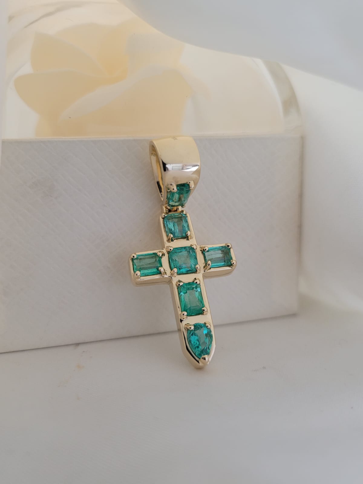 Professional photograph of a Muzo emerald cross, closeup.